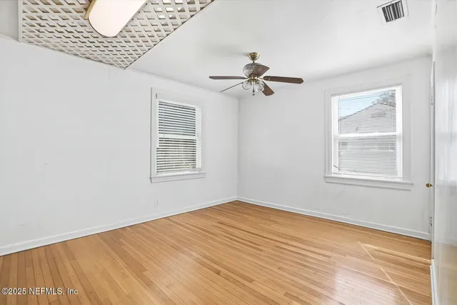 a view of empty room with wooden floor and fan