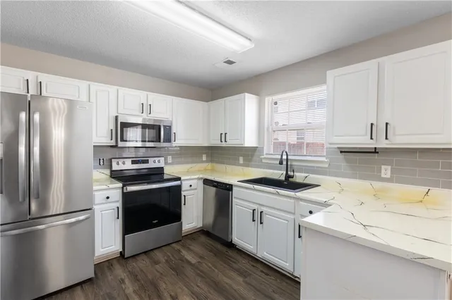 a kitchen with a sink white cabinets and stainless steel appliances