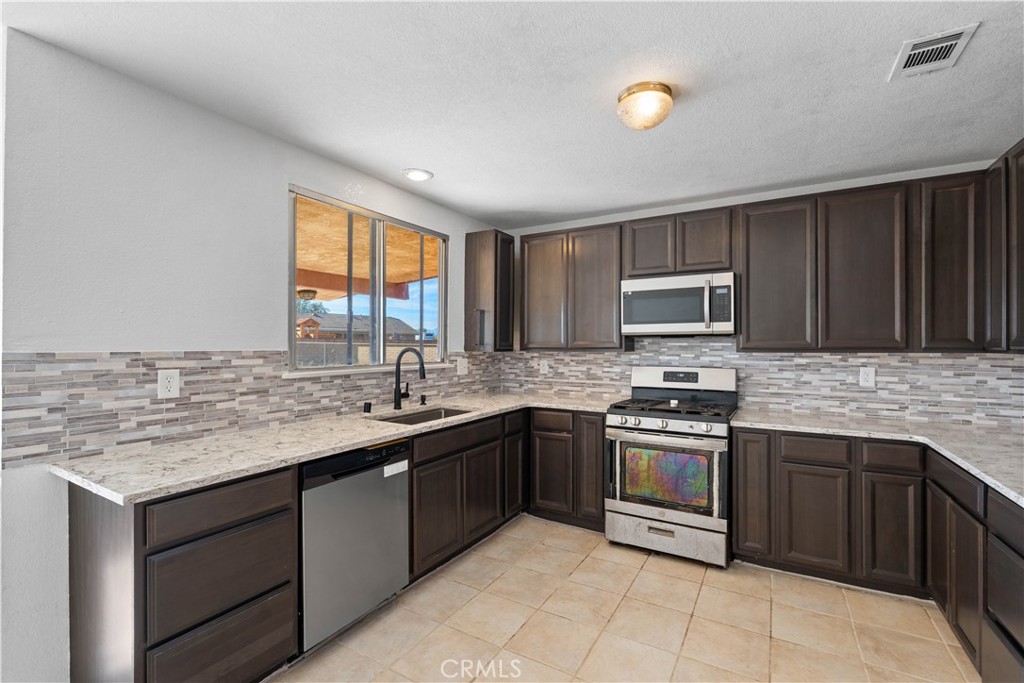 18891 Shoshonee Road Apple Valley, CA 92307 - Photo 8 of 33 a kitchen with stainless steel appliances granite countertop a stove sink and cabinets