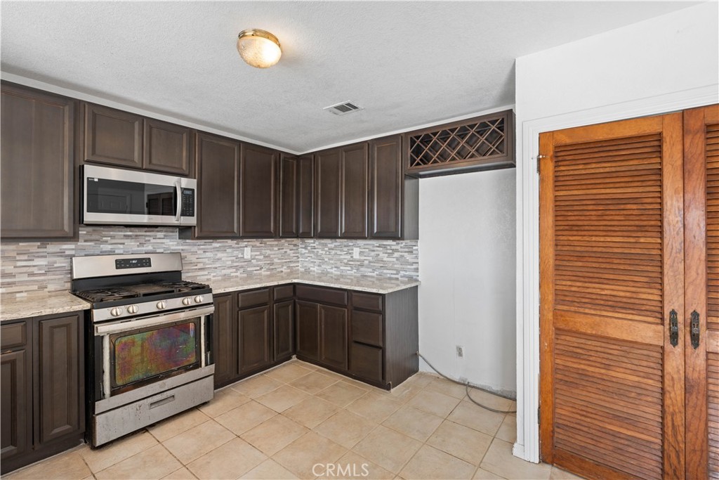 18891 Shoshonee Road Apple Valley, CA 92307 - Photo 9 of 33 a kitchen with stainless steel appliances granite countertop a refrigerator and a stove top oven