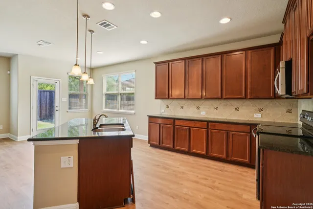a kitchen with kitchen island granite countertop a sink window and cabinets