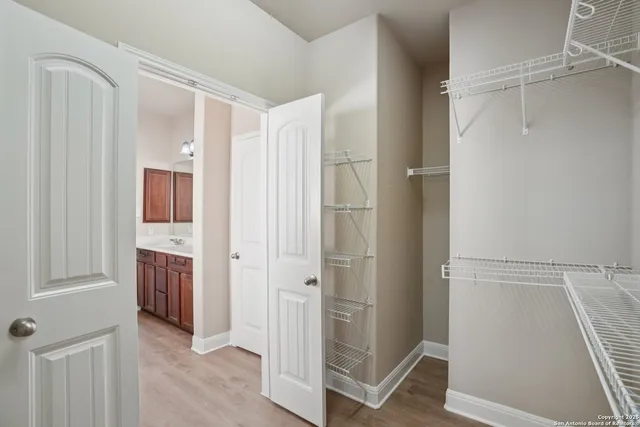 a view of walk in closet with hardwood floor