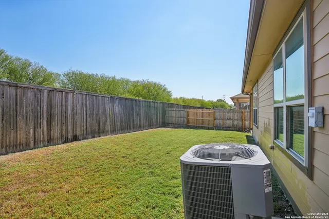 a view of a backyard with a barbeque and wooden fence