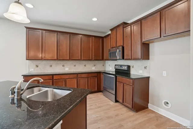 a kitchen with granite countertop a sink stove and cabinets