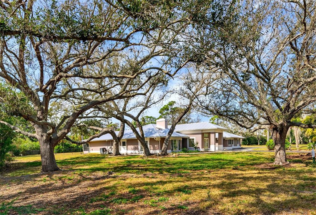 7108 Midnight Pass Road Sarasota, FL 34242 - Photo 62 of 83 a white house with a big yard and large trees