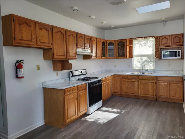 a kitchen with granite countertop a sink cabinets stainless steel appliances and a window