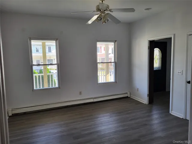 an empty room with wooden floor chandelier fan and windows
