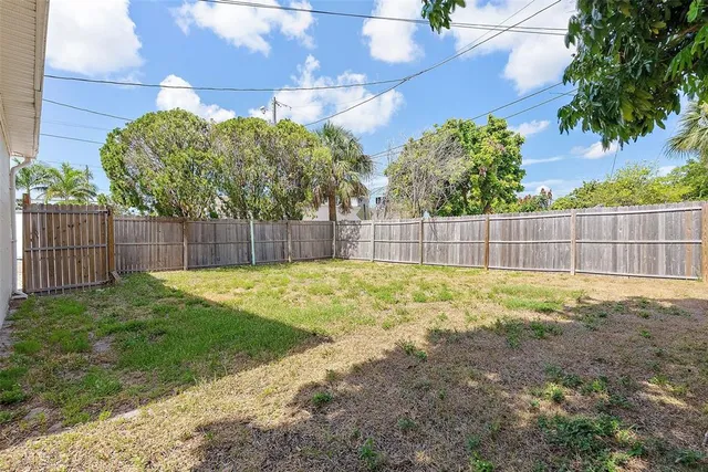 a view of a backyard with a large tree and wooden fence