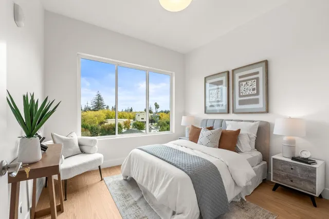 a bedroom with a bed table flowerpot and window