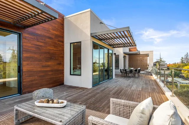 a view of a patio with couches table and chairs with wooden floor and fence