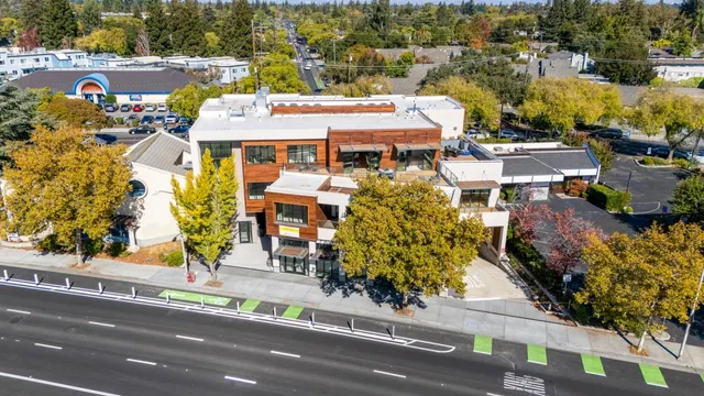 an aerial view of a residential apartment building with a yard and parking spaces