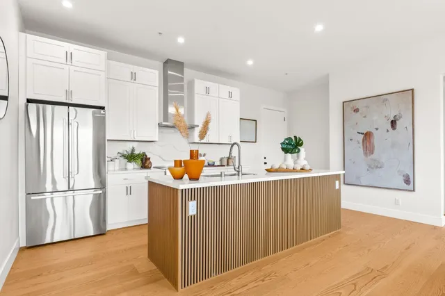a kitchen with stainless steel appliances a refrigerator and a wooden floor