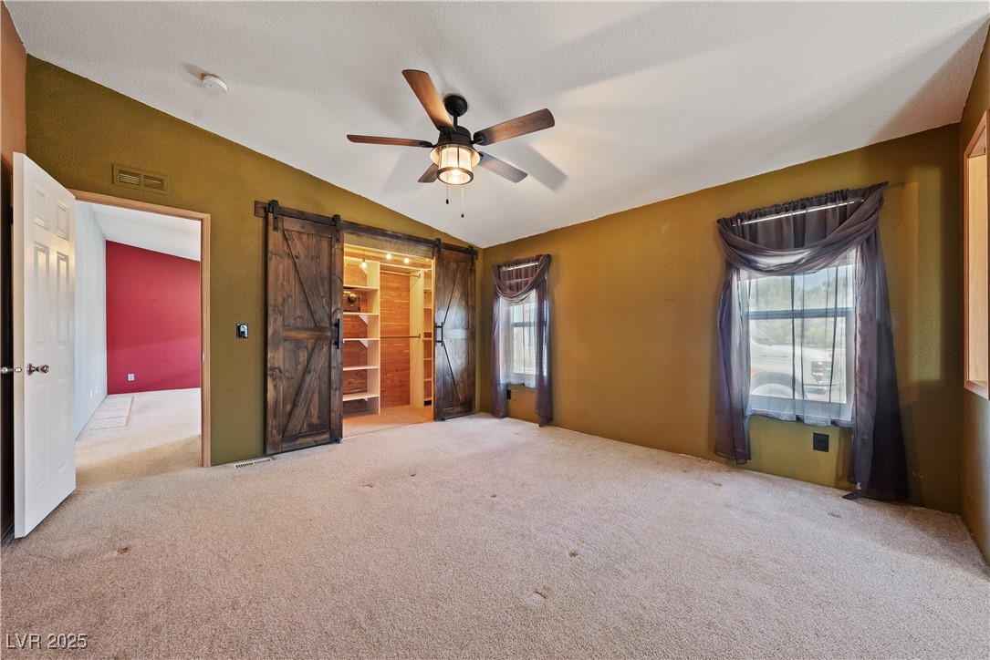 1391 East Casey Road Pahrump, NV 89048 - Photo 24 of 40 Spare room featuring a barn door, ceiling fan, carpet flooring, lofted ceiling, and a smoke detector