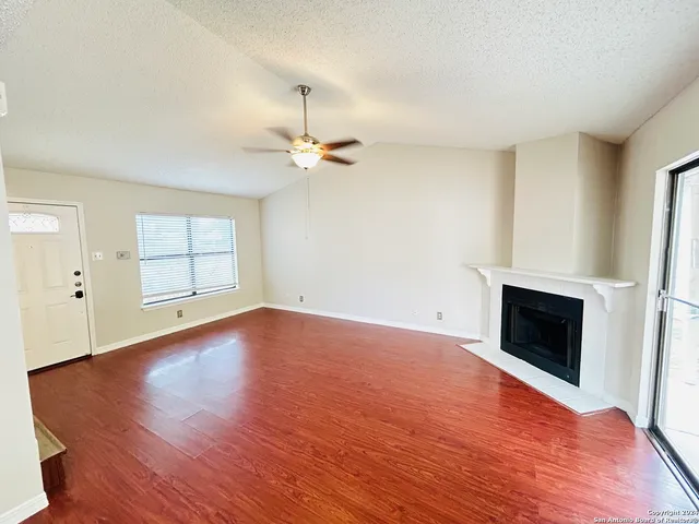 an empty room with windows and fireplace