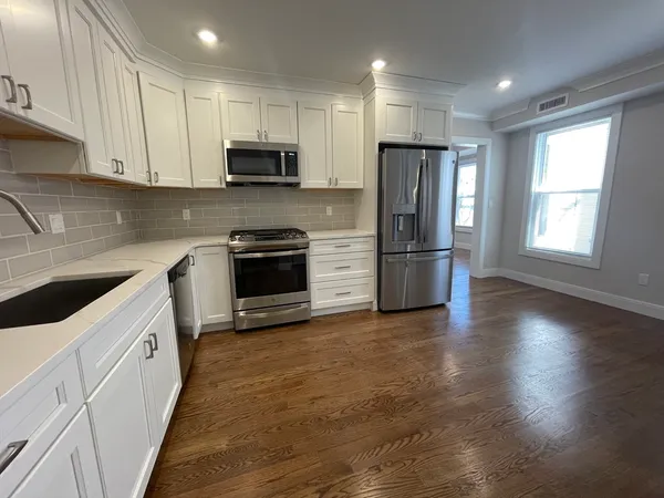 a kitchen with granite countertop a refrigerator and a stove top oven