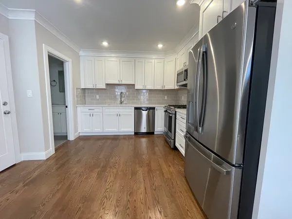 a kitchen with stainless steel appliances a refrigerator and wooden floor