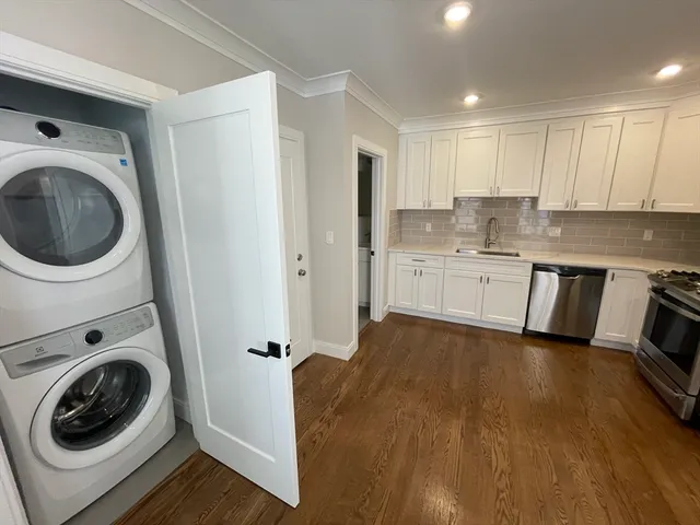 a kitchen with a sink a washer and dryer with wooden floor