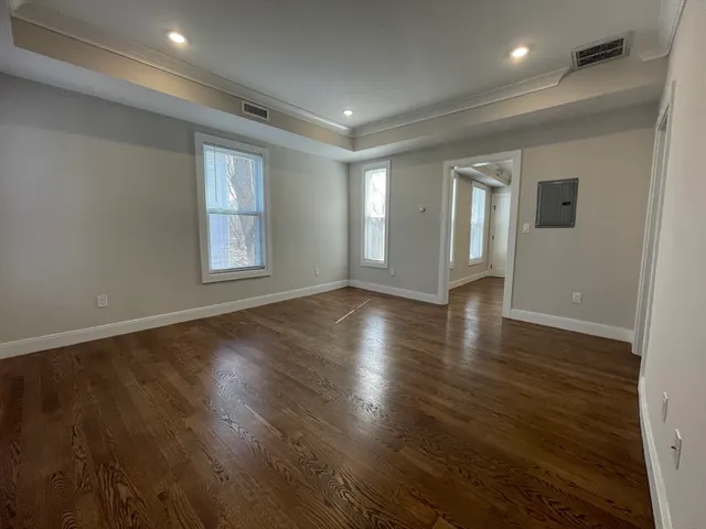 an empty room with wooden floor and windows