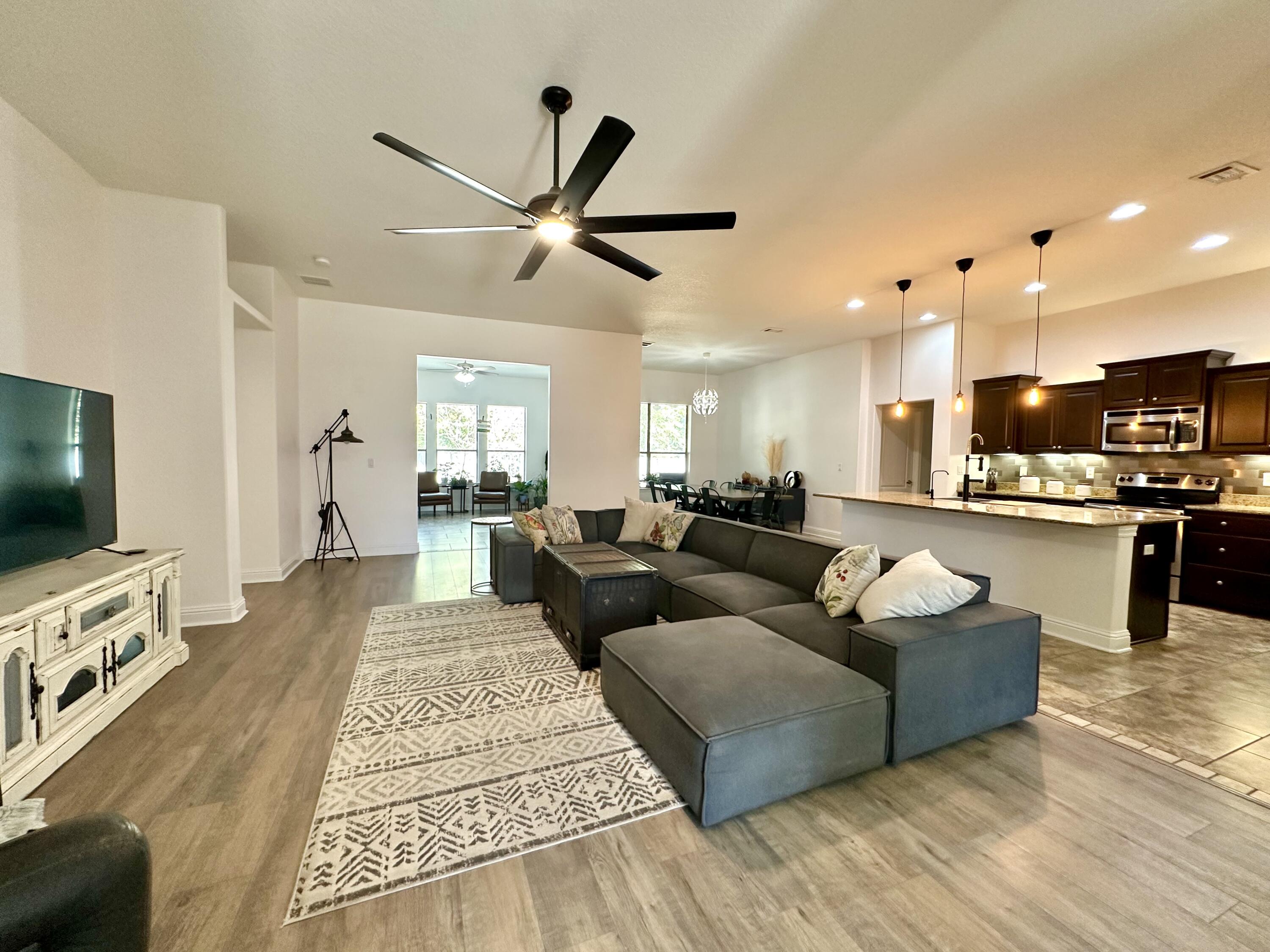5930 Wind Trace Road Crestview, FL 32536 - Photo 14 of 68 a living room with couches and kitchen view with wooden floor