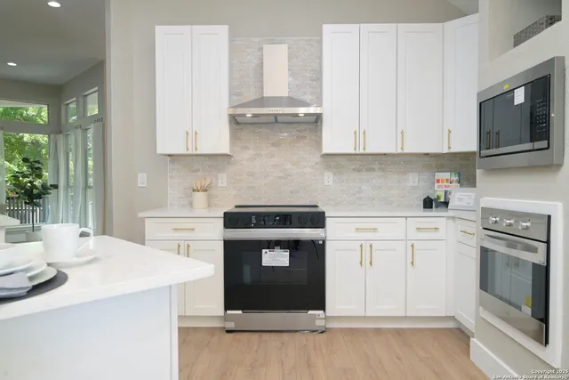 a kitchen with stainless steel appliances granite countertop a stove a sink and white cabinets