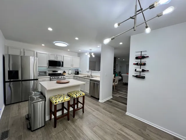 a kitchen with a sink a stove a refrigerator and white cabinets with wooden floor