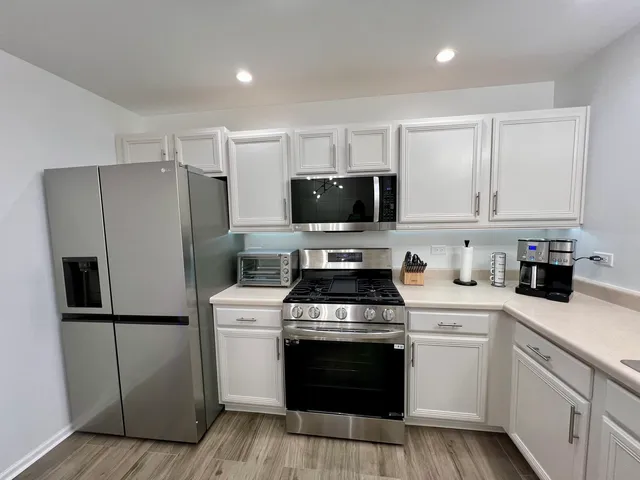 a kitchen with a refrigerator a microwave oven a sink and chairs