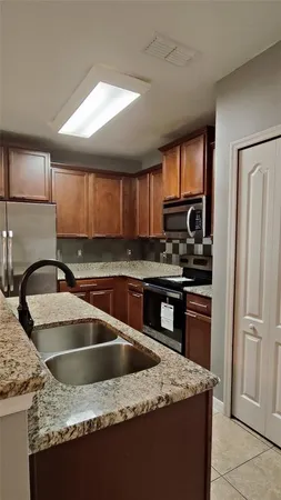 a kitchen with granite countertop a sink cabinets and stainless steel appliances