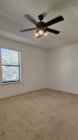 an empty room with a ceiling fan and window