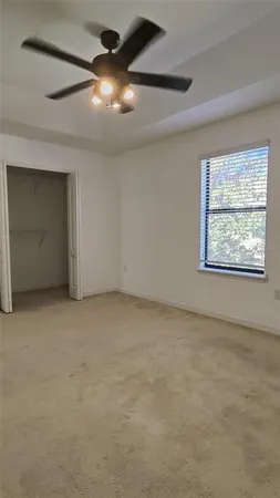 an empty room with a ceiling fan and window