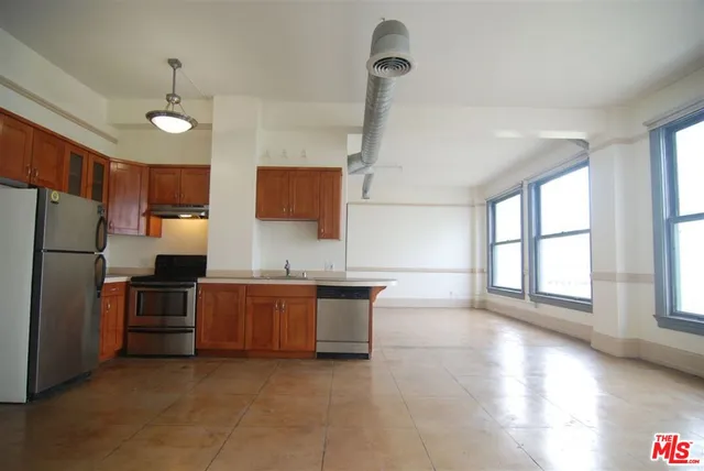 a kitchen with stainless steel appliances granite countertop a refrigerator a sink dishwasher a stove and a refrigerator with wooden floor