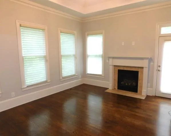 an empty room with wooden floor fireplace and windows