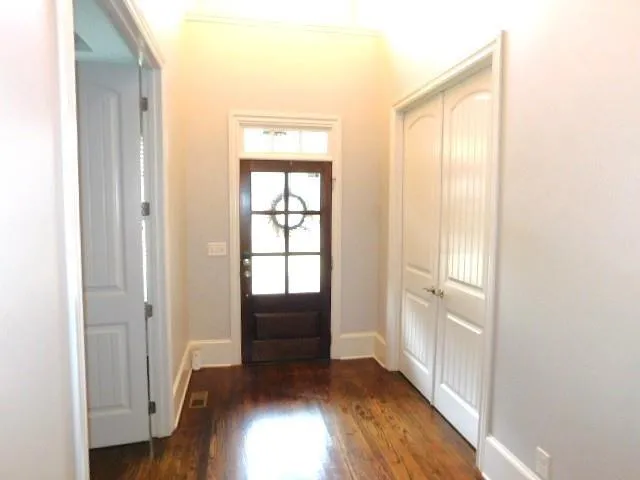 a view of hallway with window and wooden floor