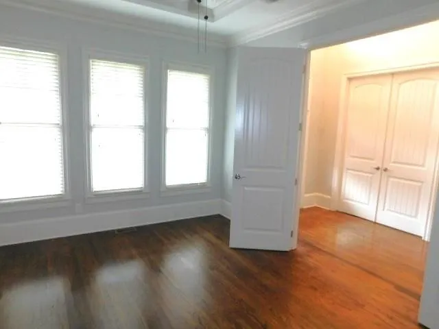 an empty room with wooden floor and windows with curtains