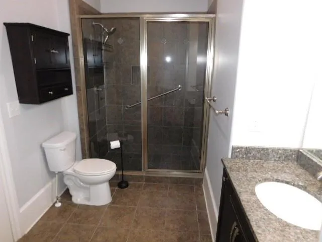 a bathroom with a granite countertop sink a toilet and shower