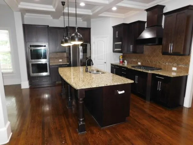 a kitchen with stainless steel appliances granite countertop a sink a stove and refrigerator