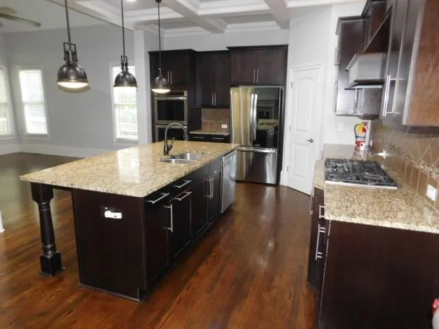 a kitchen with stainless steel appliances granite countertop a sink dishwasher a refrigerator and a stove with wooden floor