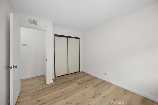 a view of an empty room with wooden floor and closet area