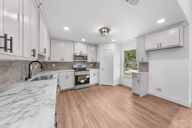 a kitchen with granite countertop white cabinets and stainless steel appliances