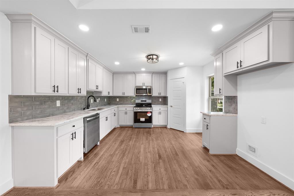 104 Mockingbird Street Ector, TX 75439 - Photo 12 of 40 a large kitchen with cabinets wooden floor and stainless steel appliances