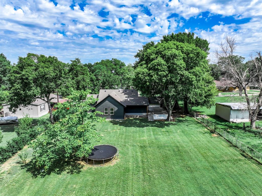 104 Mockingbird Street Ector, TX 75439 - Photo 34 of 40 a view of a backyard with potted plants and a large tree