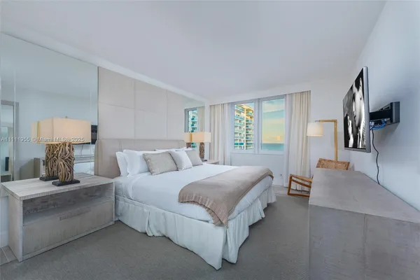 a bedroom with a bed lamp on desk and a window