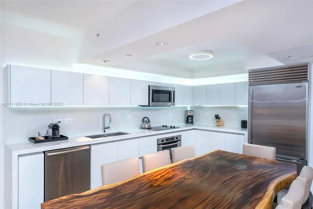 a kitchen with a sink dishwasher a stove a microwave oven and a refrigerator with wooden floor