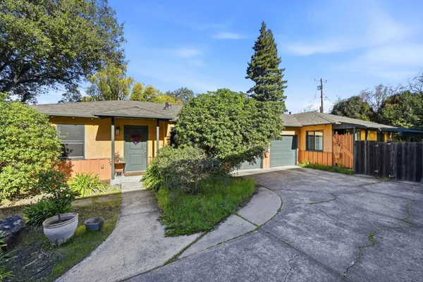 a front view of a house with a yard and potted plants