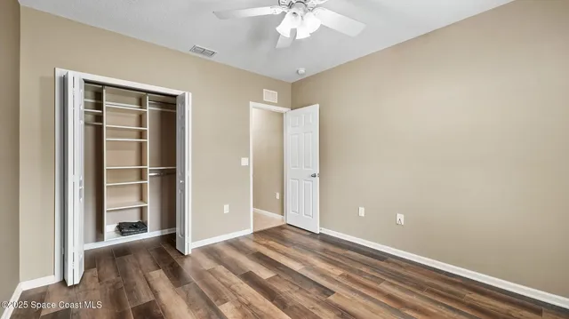 an empty room with a window and a ceiling fan