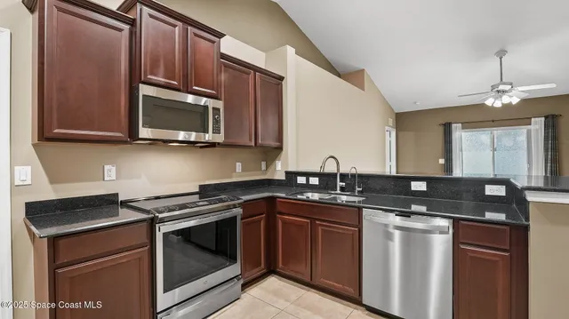 a kitchen with granite countertop a sink stove and microwave