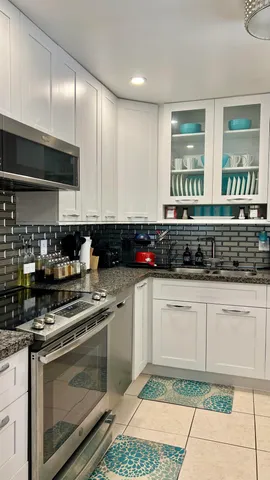 a kitchen with stainless steel appliances granite countertop a stove a sink and white cabinets