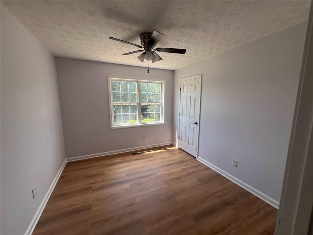 89 Farm Brook Lane Dallas, GA 30157 - Photo 20 of 42 an empty room with wooden floor chandelier fan and windows
