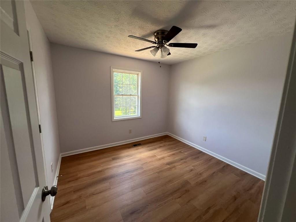 89 Farm Brook Lane Dallas, GA 30157 - Photo 22 of 42 an empty room with wooden floor fan and windows