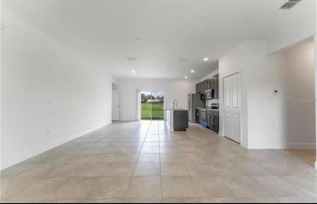 a view of a kitchen with a sink and an empty room