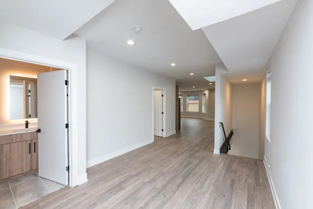 a view of a hallway with wooden floor and a bathroom